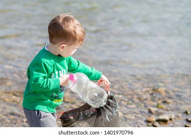 Save environment concept, a little boy collecting garbage and plastic bottles on the beach to dumped into the trash - Powered by Shutterstock