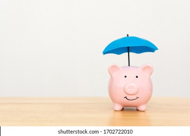 Save money and investment concept. Piggy bank and umbrella on wooden table and copy space