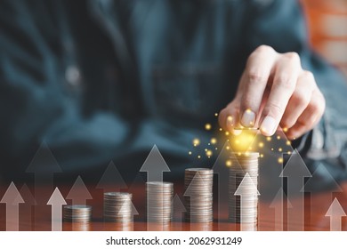 Save money and investment growth concept. Businessman hand holding coin on stack coins with white arrows rising. Financial and business, Management money for retire, tax, bank deposit, accounting.
