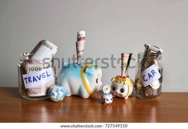 Save money for travel and car concept, piggy\
with banknote inserted and miniature airplane, world globe and car\
on jar full with money on wood\
table