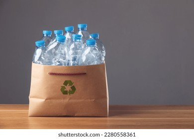 Save world and environment concept. Used blue plastic bottle in brown cardboard bag on wooden desk and dark background, Can use for reuse, recycle and environment concept. Studio shot. - Powered by Shutterstock