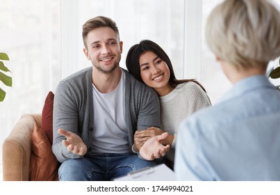 Saved marriage. Joyful multiracial couple hugging happily after psychotherapy session with marital therapist in office. Selective focus