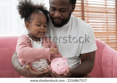 Saving and banking money concept. Girl kid putting money into the piggybank. African American girl kid inserting a coin in a piggy bank. Kid investment for future concept
