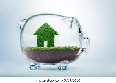 Saving to buy a house or home savings concept with grass growing in shape of house inside transparent piggy bank - Shutterstock ID 370975130