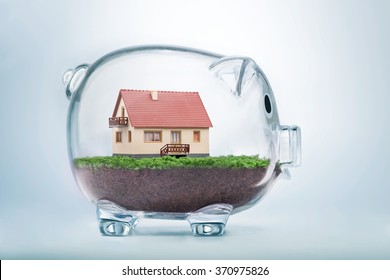 Saving to buy a house or home savings concept with model house inside transparent piggy bank - Shutterstock ID 370975826