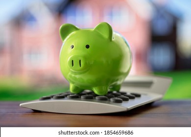 Saving To Buy A House, Real Estate Or Home Savings, Piggy Bank On Calculator In Front Of Property