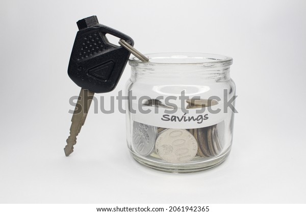 Saving coins in\
the jar and the key to the concept of consumerism in the future,\
isolated on a white\
background.