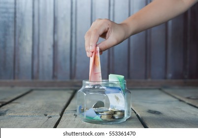 Saving concept Image Of Kid Hand Putting money Into Glass Bottle.