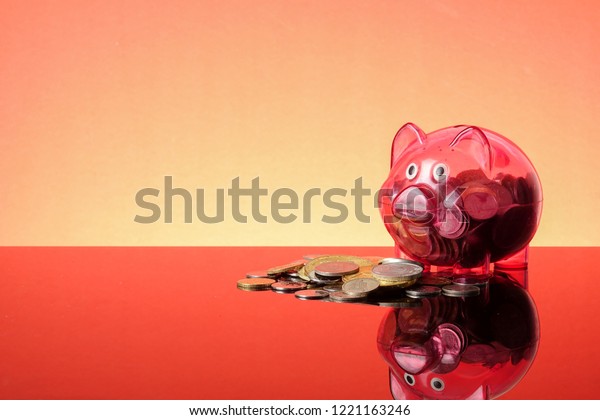 SAVING\
CONCEPT: A red piggy bank on a orange\
background.