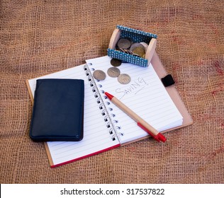 Saving concept with sack background and have a book,pen,small box,money and wallet in this photo