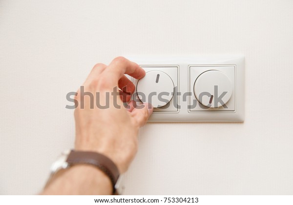 Saving energy concept: Human hand turning down\
electrical light dimmer\
switch.