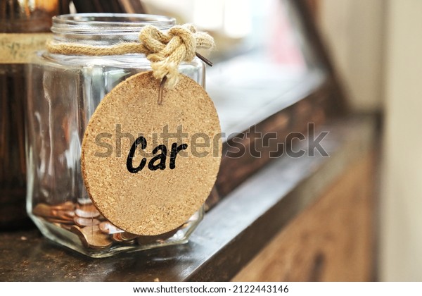 Saving money for buy car. Vintage retro glass\
jar with hemp rope tie Car tag and few coins inside on wood\
counter. spending on down payment interest. tips help lower\
interest rate and monthly\
payments
