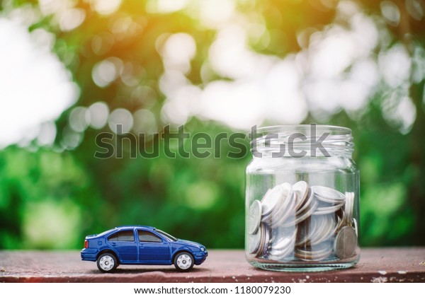 Saving money to buy a dream car. Toy cars\
and artificial light. Concept of saving\
money.