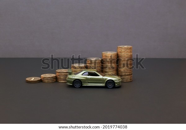 Saving money for car or\
trade car for cash, finance concept. Sell and Buy car concept. Car\
loan concept. Step of coins stacks with auto model on gray\
background. Rising\
Costs.
