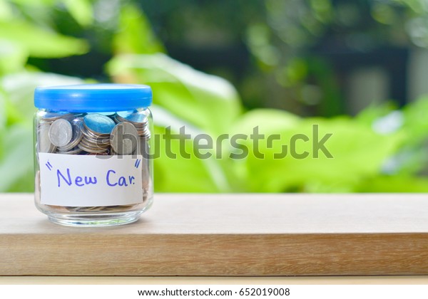 Saving money with
coin for growing your business,Thai's coin in a glass jar on wooden
texture,saving for good future life,coin  before green
background.Saving for a new
car.