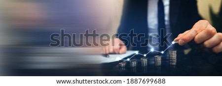 Saving money concept. Hand putting money coin stack with 
growing business graph. Panoramic business banner with  copy space.
