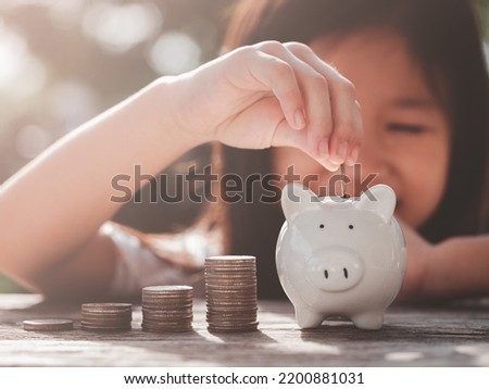 Saving Money Concept. Happy Asian child girl save money by putting coins into piggy bank, coin stack growing. Concept save money, cash, education, growth, finance, bank, management, income, business