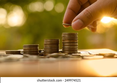 Sparen Sie Geld-Konzept von Hand von Mann, indem Sie Geld-Coin-Stack-Wachstum Geschäft