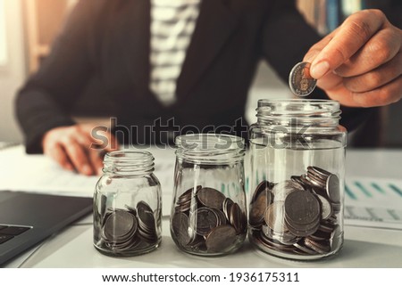 saving money with hand putting coins in jug glass concept financial