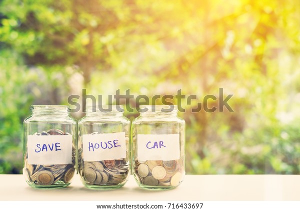 Saving money for house and car concept : Coins\
in three jars with label. Ideas of saving for a down payment on a\
car or home that allow buyers to use down payment to reduce overall\
cost of borrowing.