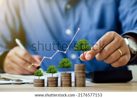 Saving money and investment concept. Businessmen put a coin with a tree that grows and a tree that grows on a pile of money. The idea of maximizing the profit from the business investment. 