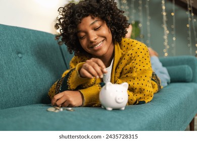 Saving money investment for future. African American girl putting money coin in pink piggy bank. Saving investment budget business wealth retirement financial money banking concept - Powered by Shutterstock