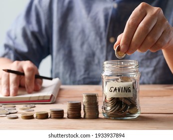 Saving Money. Man hand putting coins in a glass jar. Concept of retirement, save money and cash, finance, investing, growth management, happy, income, tax, business, financial planning.