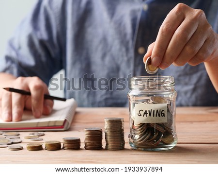 Saving Money. Man hand putting coins in a glass jar. Concept of retirement, save money and cash, finance, investing, growth management, happy, income, tax, business, financial planning.