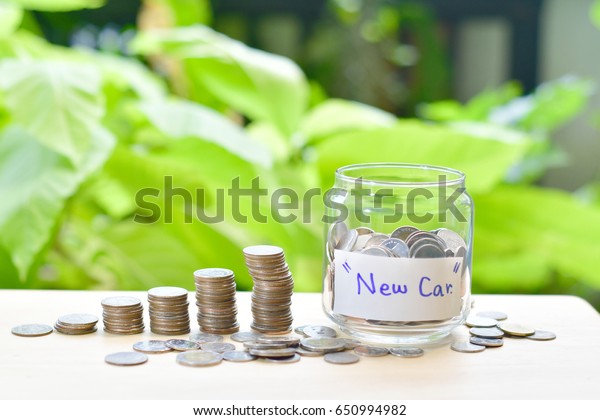 Saving money with stack money coin for growing your\
business,Thai\'s coin stacking on wooden texture,saving for good\
future life,coin stack before green background.Saving for dream,for\
new car.