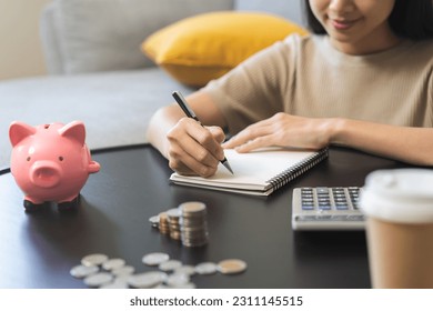 Saving money wealth concept, asian young business woman hand write management budget for saving cost, cash finance planning to spend enough money on her income for save money, payment tax, investing. - Powered by Shutterstock