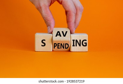 Saving or spending symbol. Businessman turns cubes and changes the word 'spending' to 'saving'. Beautiful orange table, orange background, copy space. Business and saving or spending concept. - Shutterstock ID 1928537219