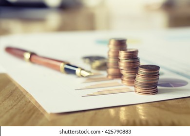 Saving stack coins money concept,graph,chart  document and pen on desktop desk in hipster office,copy space.selective focus,vintage color - Shutterstock ID 425790883