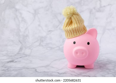 Savings concept. Piggy bank and money on a textural background. A piggy bank in a warm winter hat that saves heat. The concept of saving heating. Place for text. copy space - Powered by Shutterstock