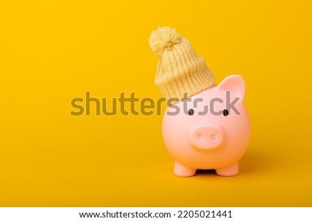 Savings concept. Piggy bank on a yellow textural background. A piggy bank in a warm winter hat that keeps you warm. Heat saving concept. Place for text. copy space