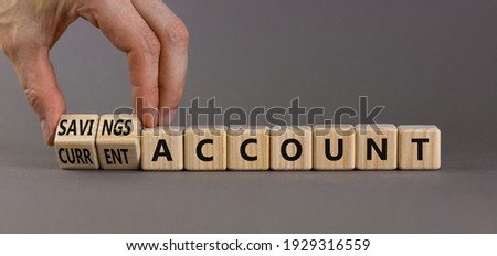 Savings or current account symbol. Businessman turns wooden cubes and changes words 'current account' to 'savings account'. Beautiful grey background, copy space. Business concept.