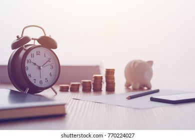 Savings, Finances, Economy And Home Budget Calculations. Vintage Clock, Piggy Bank And Coins Stacked On Home Desk.