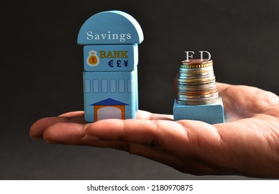 Savings And Fixed Deposit Concept With Hand Holding Bank Model And Currency