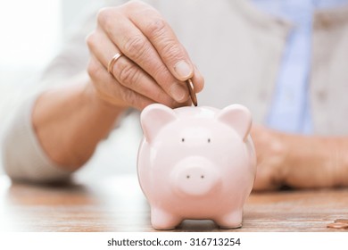 Savings, Money, Annuity Insurance, Retirement And People Concept - Close Up Of Senior Woman Hand Putting Coin Into Piggy Bank