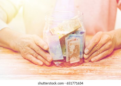 savings, money, annuity insurance, retirement and people concept - close up of senior woman hands with money in glass jar