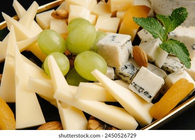 Savor a chic cheese platter with brie, cheddar, and gouda cheeses, paired with grapes, almonds, and oranges on a slate plate - perfect for entertaining or a classy snack. - Powered by Shutterstock