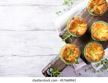 Savory cheddar cheese and leek mini quiches with thyme on dark wooden cutting board. Top view with copy space
