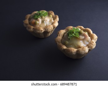 Savory Danish tartlets (tarteletter) made from puff pastry, filled with a creamy chicken, asparagus and carrot sauce. Isolated on black background