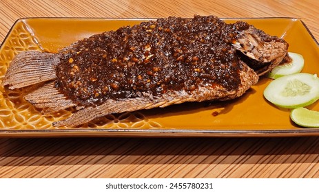 Savory Grilled Gurame Fish with Candlenut Spice on Elegant Golden Plate. - Powered by Shutterstock