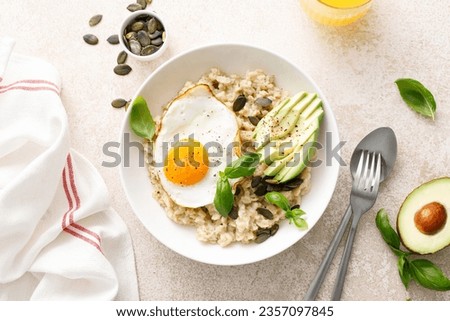 Savory oatmeal with fried sunny side up egg, avocado and pumpkin seeds for healthy breakfast
