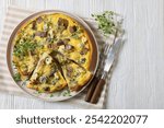 savory omelette with blue cheese, rye croutons and fresh thyme on plate on white wooden table with cutlery, horizontal view from above, free space, flat lay