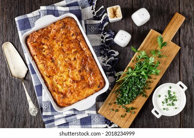 savory potato kugel, baked pudding or casserole of grated potato in a baking dish on a wooden table, jewish holiday recipe, flat lay
