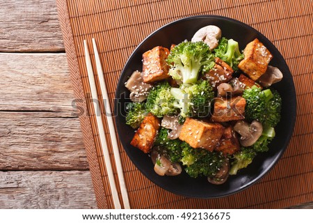Savory sauteed mixed chinese vegetables with crispy fried tofu on a plate. Horizontal view from above
