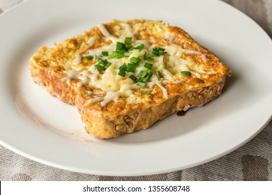 Savoury Cheesy French Toast Slice With Chives Garnish Close Up On White Plate