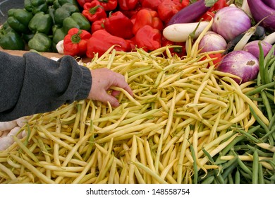 A Savvy Shopper Selects Fresh Picked Beans At An Outdoor Farmers Market Produce Stand. The Produce Stand Also Has Peppers, Garlic And Eggplant.  