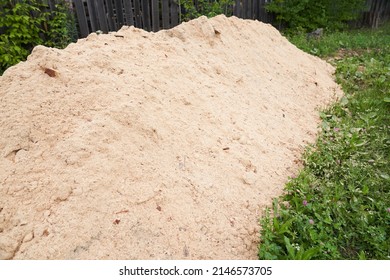 Sawdust stacked in a slide against the background of the lawn. The background is made of natural sawdust. Recycling of woodworking waste. High quality photo